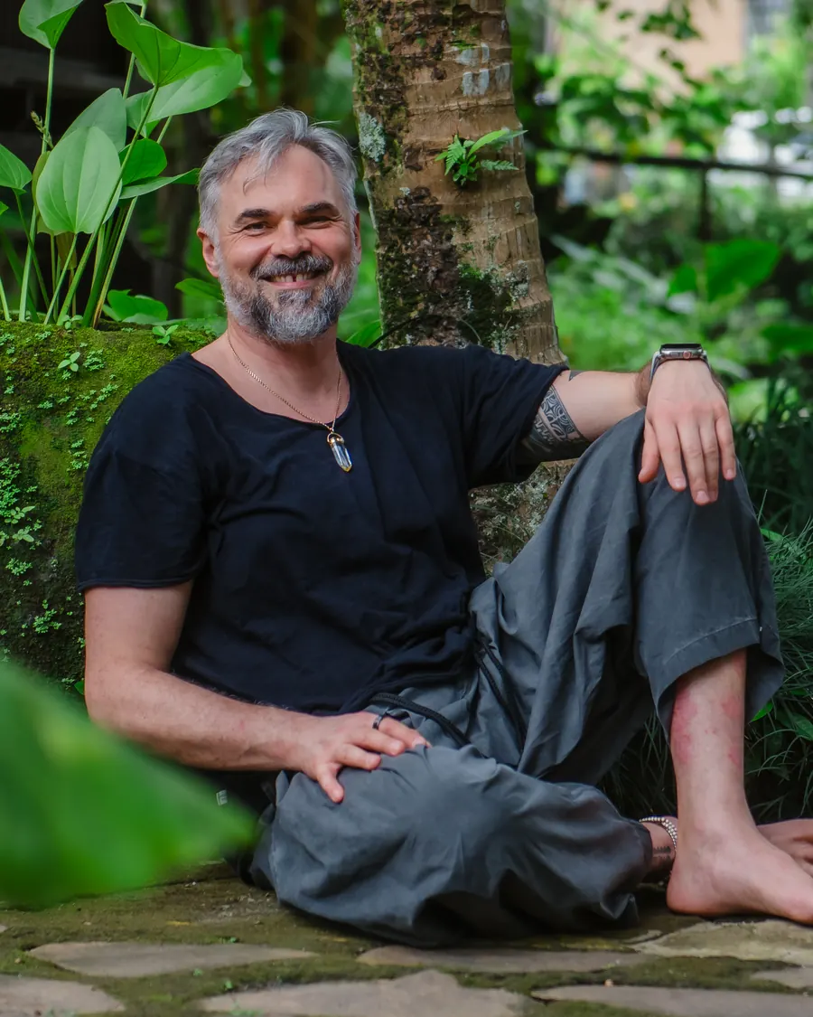 Nisarga Eryk Dobosz sitting relaxed in a garden, smiling